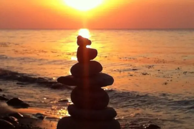 Steinturm am Strand beim Sonnenaufgang steht für Prioritäten im Führungsalltag setzen