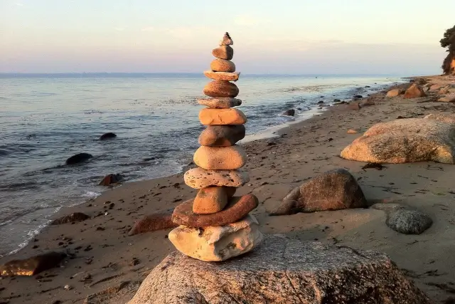 Steinturm am Strand symbolisiert neue Routinen in den Führungsarbeitstag zu integrieren