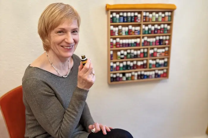 lächelnde Frau mit Flasche ätherischen Öls in der Hand