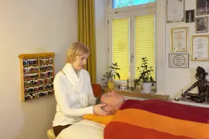 Frau massiert Person am Kopf